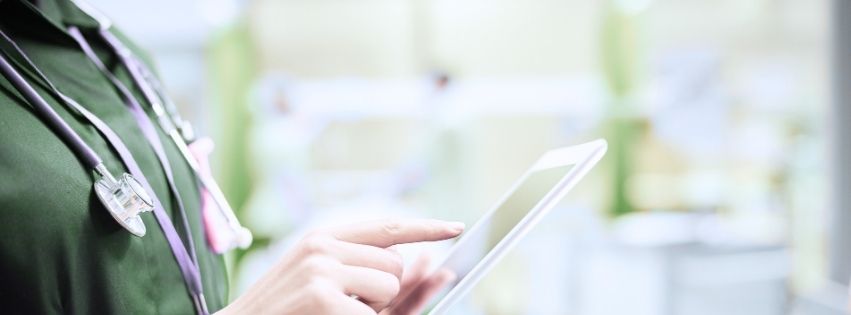 Close-up of a nurse in green scrubs and stethoscope using a tablet, representing 24/7 digital support for pregnancy centers.