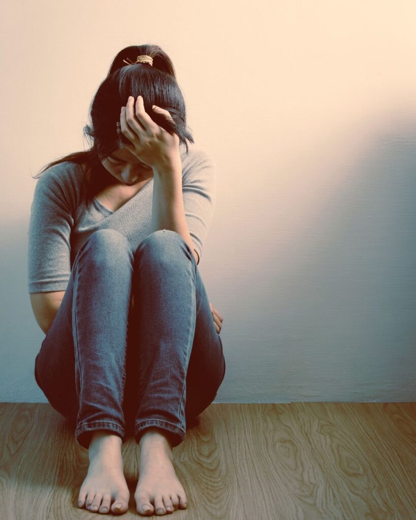 woman sitting on floor obviously distraught, abortion's unspoken toll on mental health.