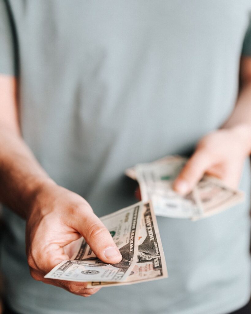 man holding money out to donate