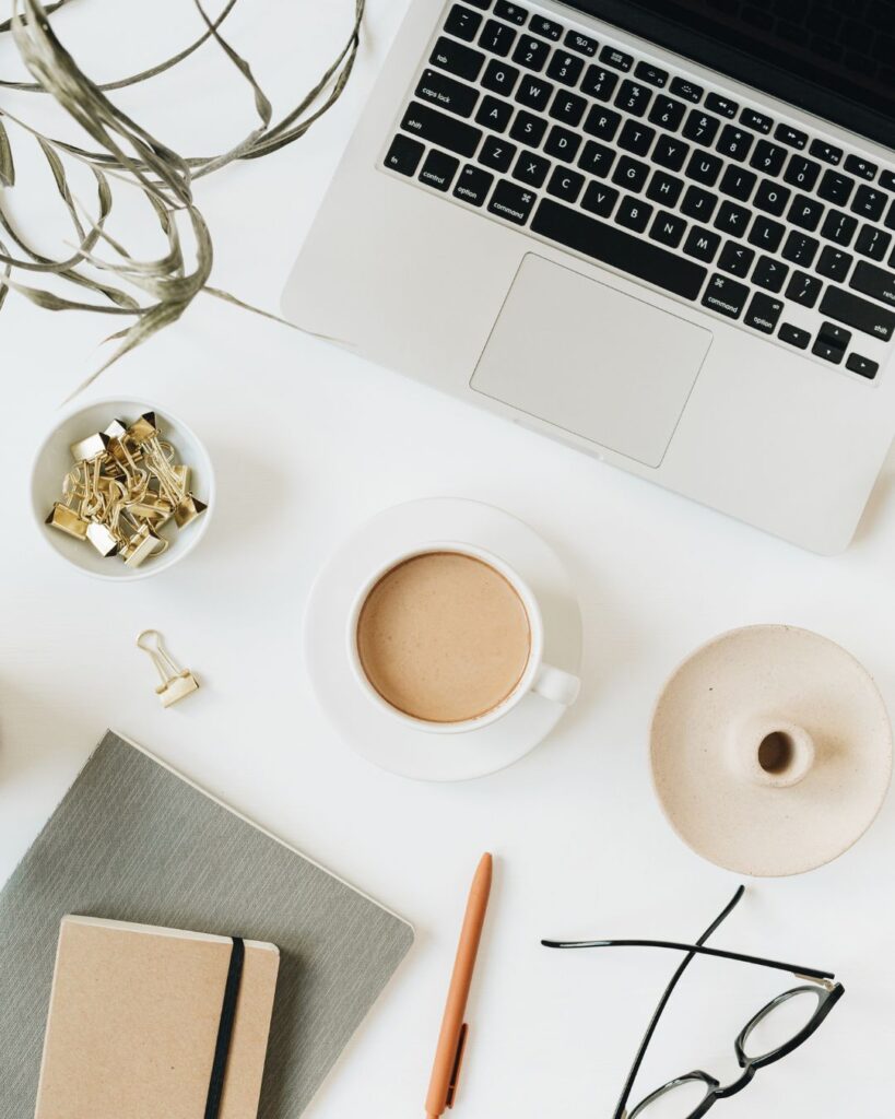 Flat lay of an office desk, coffee, glasses, computer, and notes. AI optimization for today's websites.